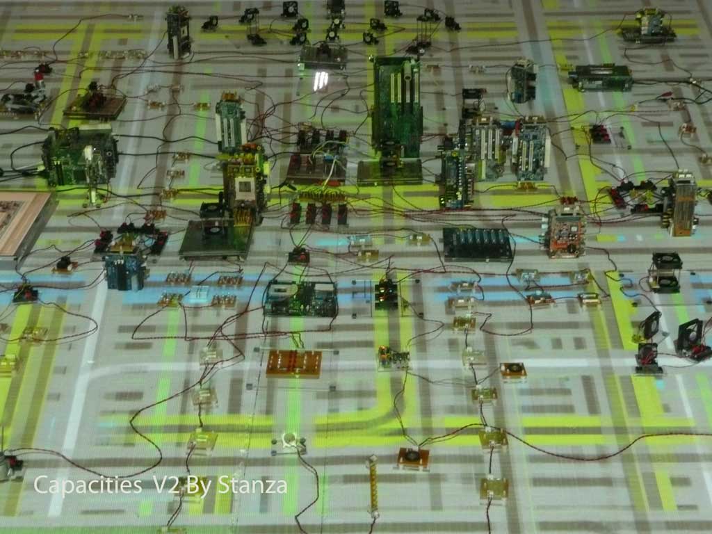 Capacities by Stanza. The installation is about the real time city, making artworks using live data.Essentially this artwork gathers data from the city this is then made virtual and then this virtual city is represented as this electronic city. A manipulation of data, that &lsquo;powers&rsquo; all the &lsquo;events&rsquo; in the installation.The changing data affects all the changes one experiences in the space. ie the moving objects, fans&nbsp;and changing&nbsp;lights are all responding to changes in temperature, light, pressure, noise, and&nbsp;the sound of the space.Essentially this artwork gathers data from the city (environment) this is then made virtual and then this virtual city is represented as this electronic city